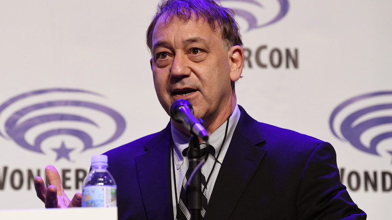 Sam Raimi in a suit in front of a microphone