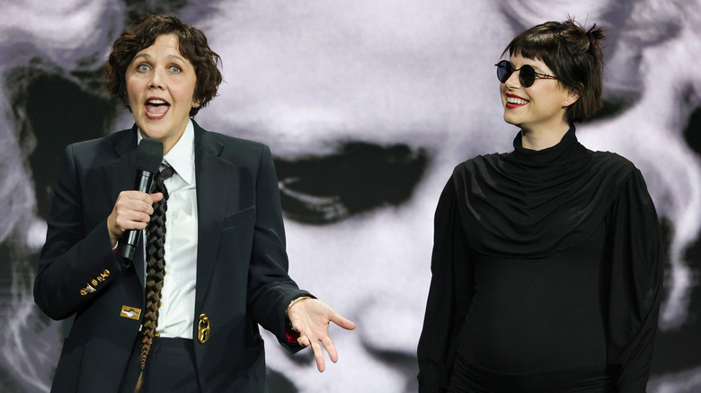 Maggie Gyllenhaal and Jessie Buckley in front of a poster for "The Bride!" (2026)