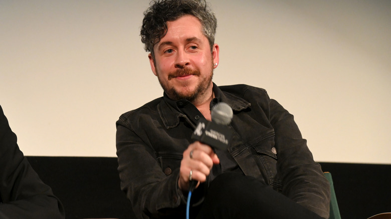 Lee Cronin sitting on stage holding a microphone