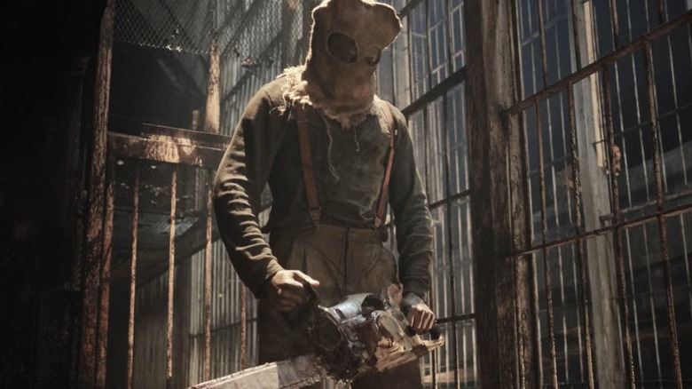 A masked man wielding a chainsaw among prison cells in "Resident Evil" (2022)