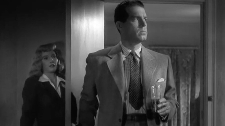 Walter walks through a door holding a drink in Double Indemnity (1944)