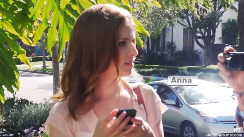 Anna Kendrick holding a phone and looking to the side