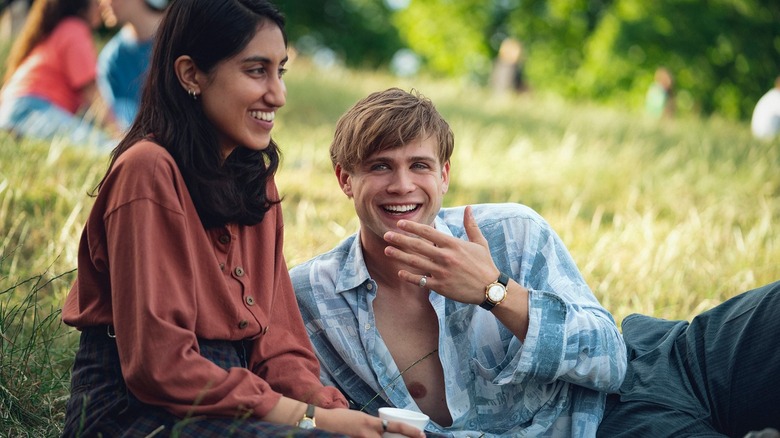 Emma and Dex laughing in the grass in One Day