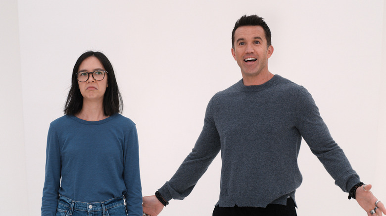 Ian smiling and Poppy frowning in an office painted all white