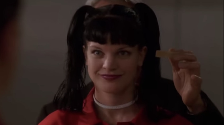 Abby Sciuto smiling with pigtails and a red coat