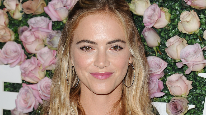 Emily Wickersham smiling flower wall