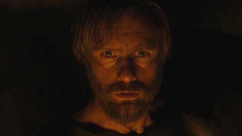 A closeup of Alexander Skarsgård as Amleth in The Northman, lit by a campfire