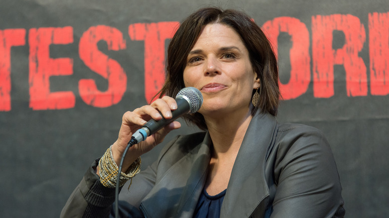 Neve Campbell holding microphone smiling