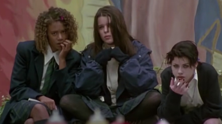 Rachel True, Neve Campbell, Fairuza Balk sit outside in front of mural
