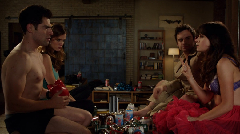 Schmidt, Holly, Nick, and Jess un various states of undressed sitting on a table