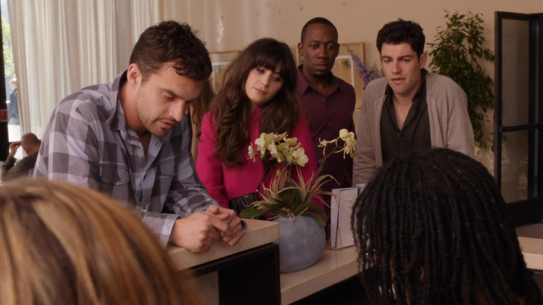 Nick signing in for his ultrasound as Jess, Winston, and Schmidt stand nearby looking worried