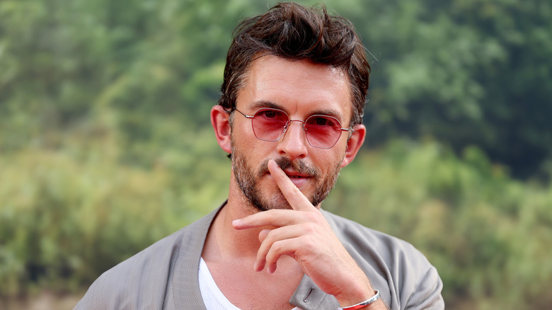 Actor Jonathan Bailey posing with his finger over his mouth at the premiere of 