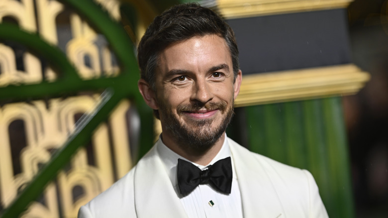 Close-up shot of actor Jonathan Bailey posing at the premiere of Wicked in a white tuxedo