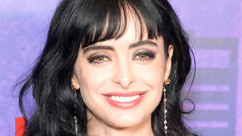 Krysten Ritter smiling with purple background