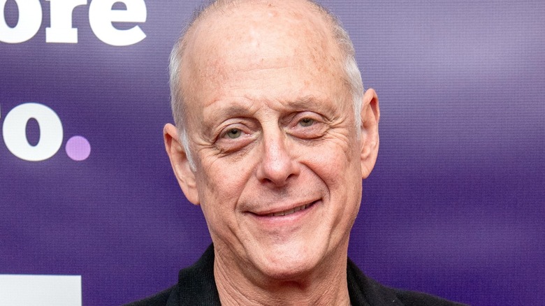 Mark Blum against purple backdrop smiling