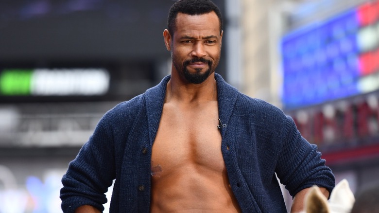 Isaiah Mustafa in an open cardigan riding a horse in Times Square