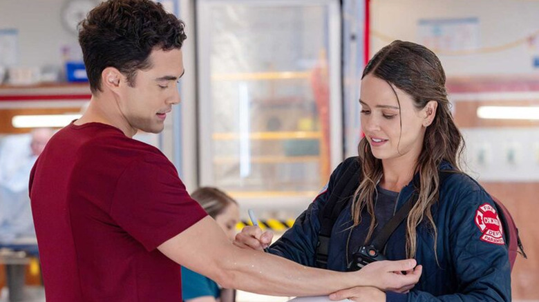 Lyla Novak writes 9-1-1 on the arm of John Frost in 