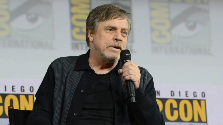 Mark Hamill holds a microphone