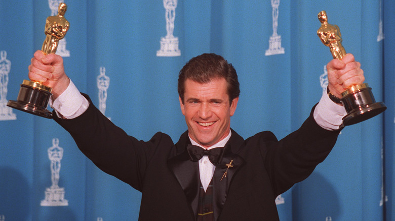 Mel Gibson holding up two Oscar statues