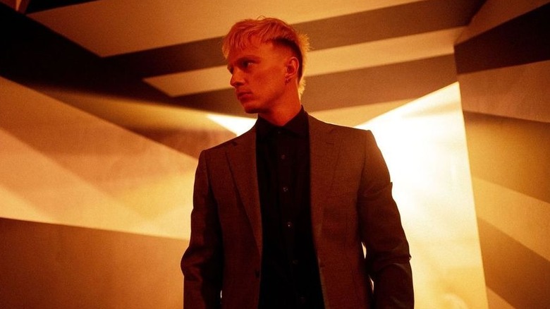 Cyrus standing against an abstract background, investigating, in "Onslaught" (2026)