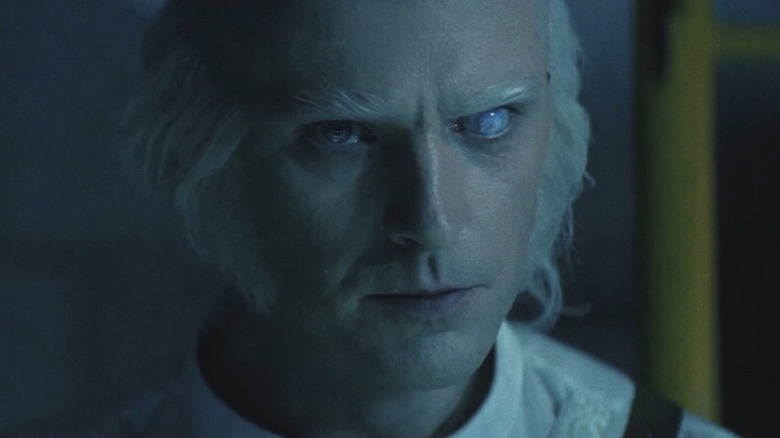 Close-up of Dr. Kammler flashing a sinister grin in "Onslaught" (2026)