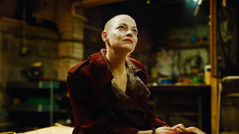 Bald Michelle looking up in the basement in Bugonia