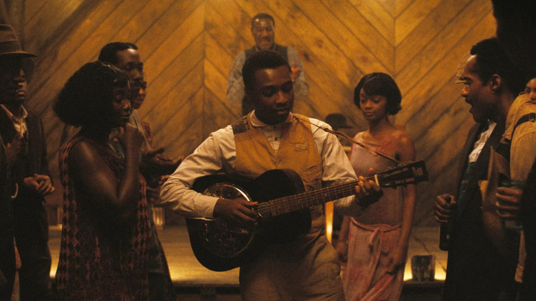 Sammy playing his guitar at the juke joint in Sinners