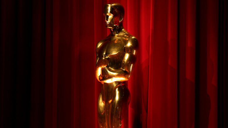 An Oscar statue in front of a red curtain