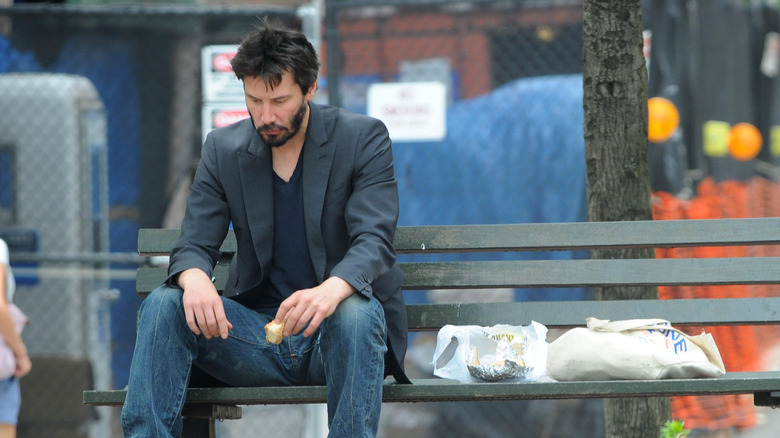 Keanu eating sandwich on a bench
