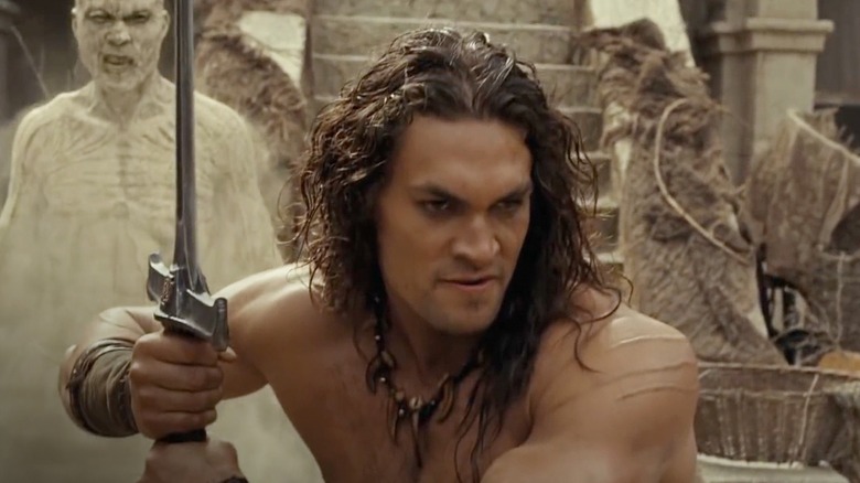 Conan holds a sword, oblivious to an enemy behind him