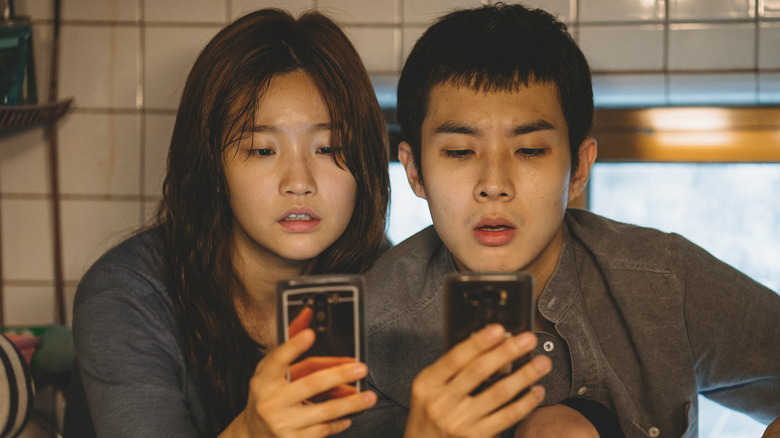 Ki-jung and Ki-woo staring at their phones