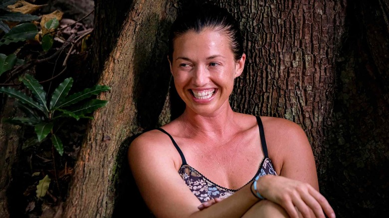 Parvati sitting against a tree and smiling on Survivor