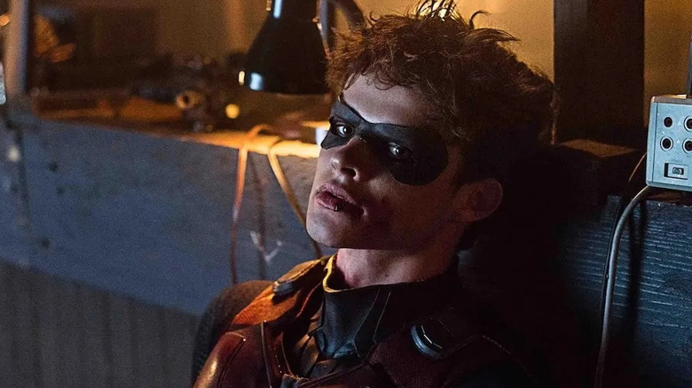 Jason Todd leans back against a wooden beam in Titans