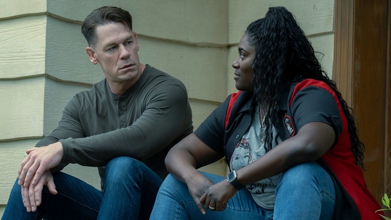Chris Smith/Peacemaker and Adebayo sitting on steps outside in "Peacemaker" Season 2