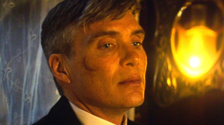 Tommy Shelby frowning next to a lamp in 
