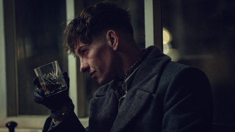 Duke tipping a glass of whiskey in 