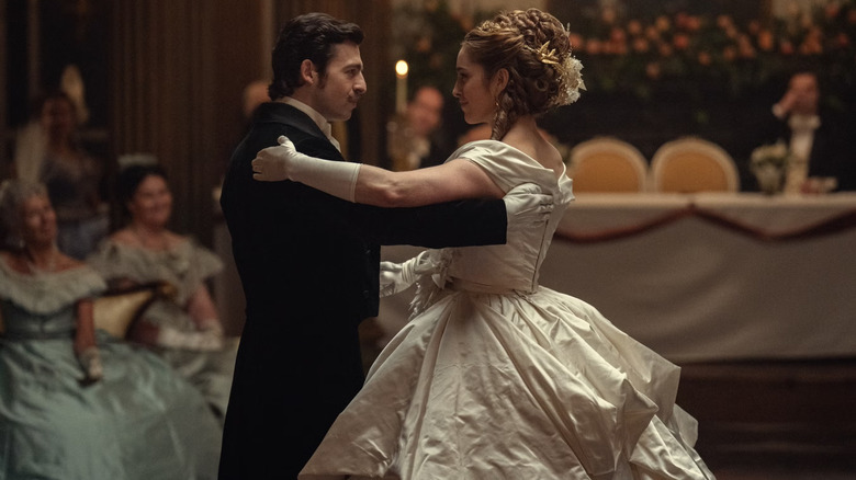 Formally-dressed newlyweds Arthur and Olivia sharing a courtly dance at their wedding