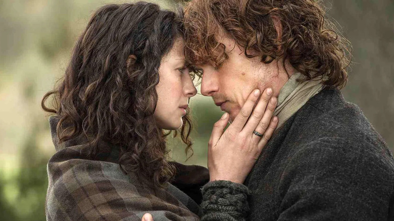 A mutually bedraggled Claire and Jamie pressing their foreheads together as Jamie closes his eyes and Claire cradles his face with her hands