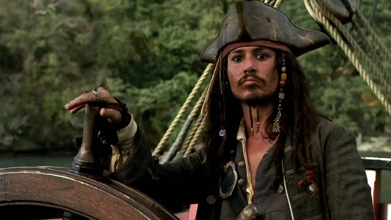 Jack Sparrow stands at the steering wheel of a ship in "Pirates of the Caribbean: The Curse of the Black Pearl" (2003)
