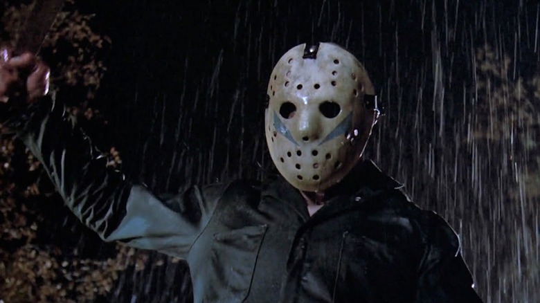 In the rain, 'Jason' raises a machete over his head in Friday the 13th Part V (1985)