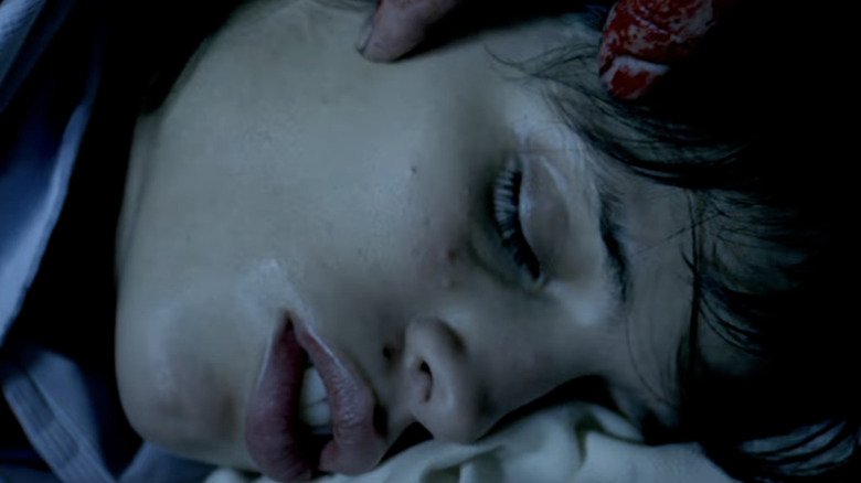 Alexia sleeps while a bloody hand reaches for her face in High Tension (2003)