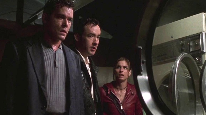 Ed, Rhodes, and Paris walk cautiously through a laundromat in Identity (2003)