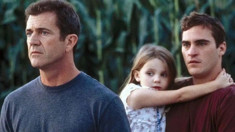 Graham, Merrill, and Bo, stand in a cornfield looking into the distance in Signs (2002)