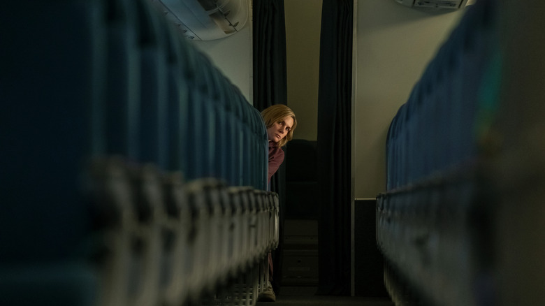 Carol sitting alone on a plane looking up the aisle
