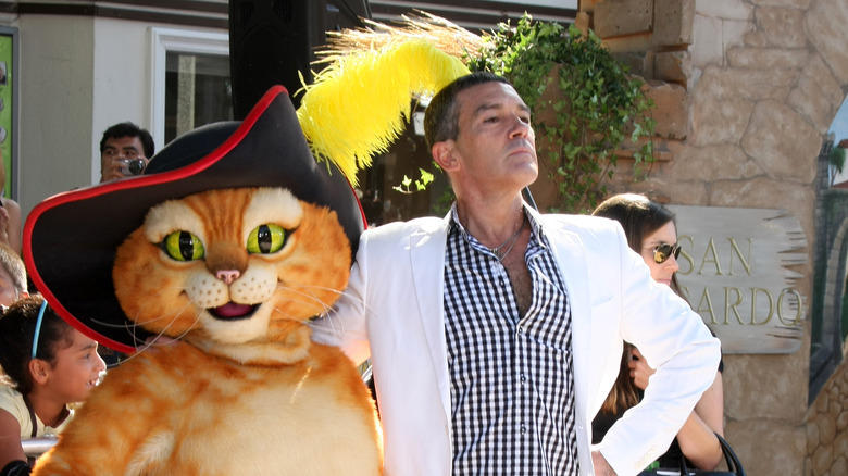 a Puss in Boots mascot and Antonio Banderas pose
