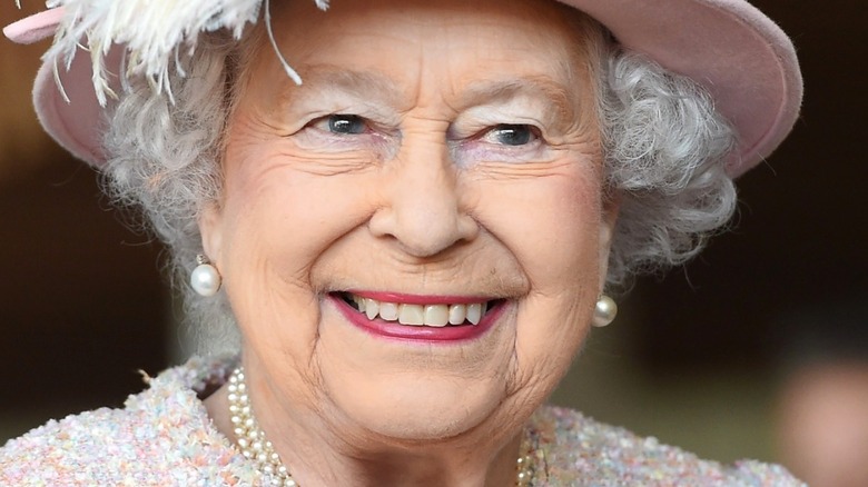 Queen Elizabeth II smiling with pink hat on 