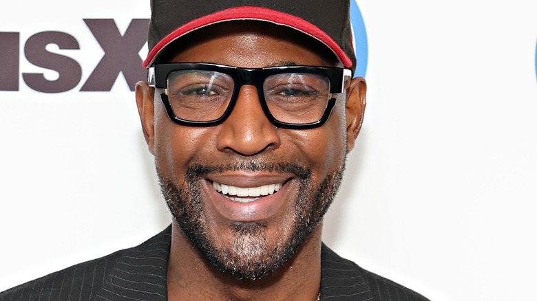 Karamo Brown with glasses and hat smiling