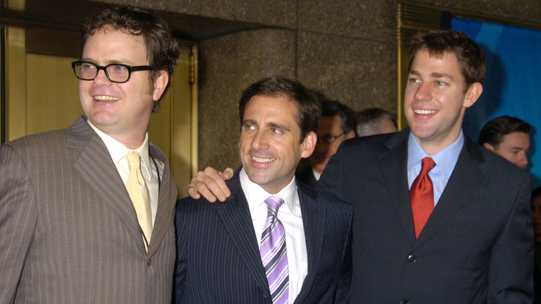 Rainn Wilson, Steve Carell, and John Krasinski smiling toward the left while promoting "The Office"