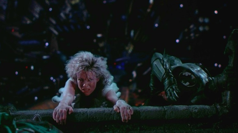 woman and batman hang off ledge