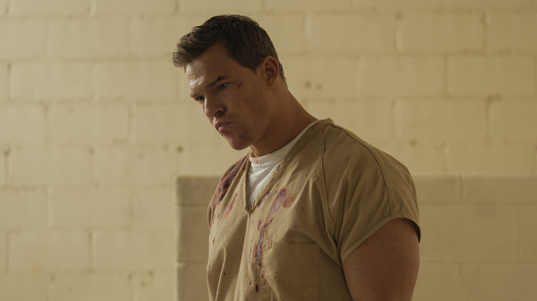 Jack Reacher wearing beige bloodstained prison uniform